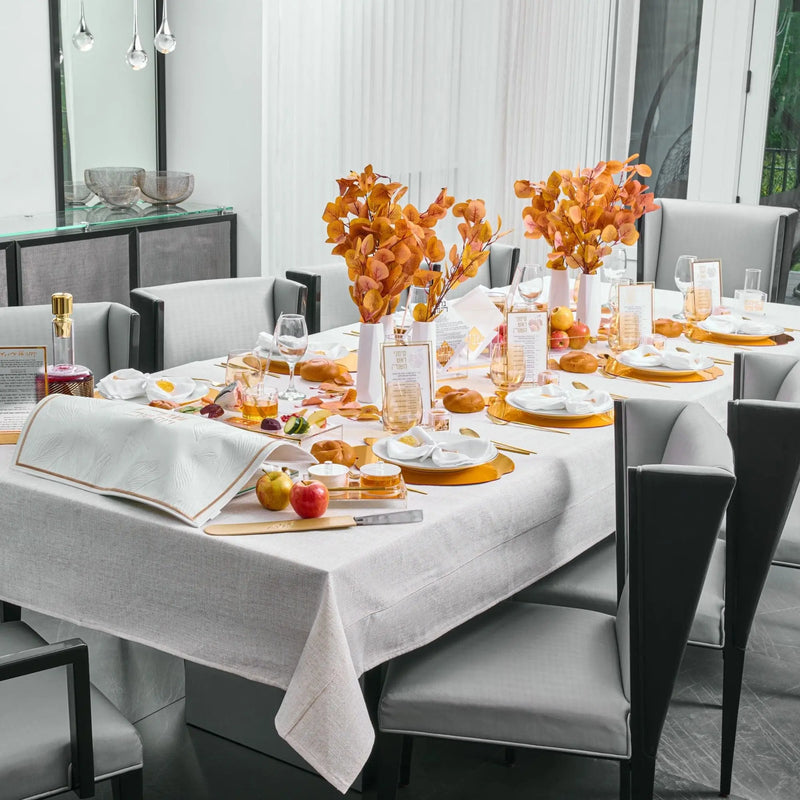 Rosh Hashanah 2025 Classic 2.0 tablescape featuring orange painted floral centerpieces, white linens, and coordinating place settings on a formal dining table.