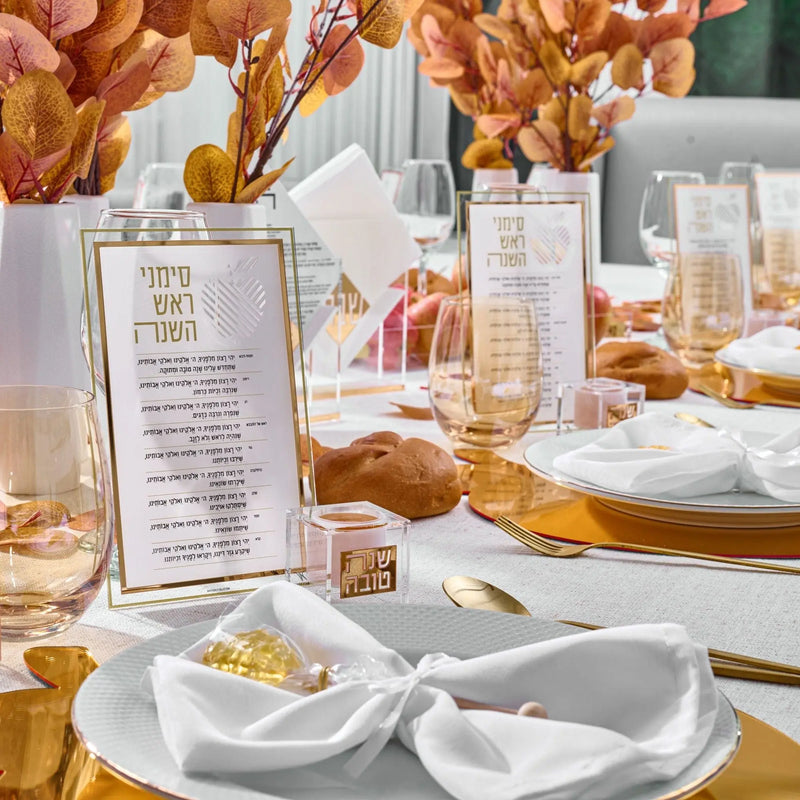 Rosh Hashanah Classic 2.0 tablescape featuring gold-painted plates, menu cards, and autumn-colored floral centerpiece on white table setting.