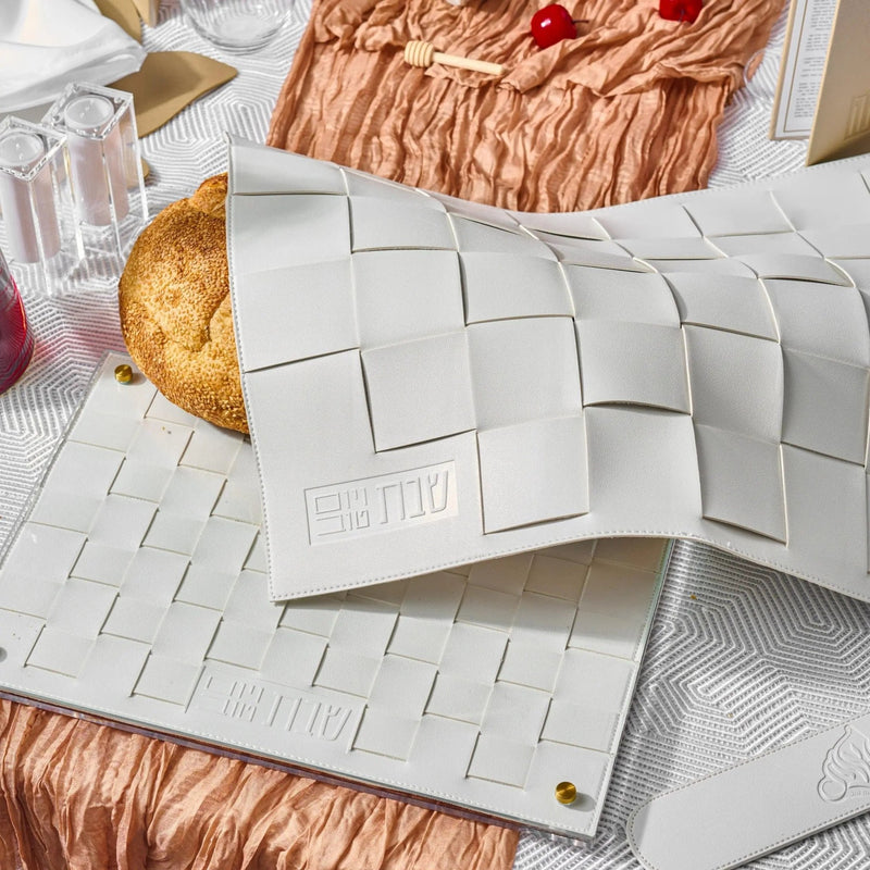White painted Rosh Hashanah tablescape placemats arranged on copper fabric with decorative gold accents and fresh bread by Waterdale Collection