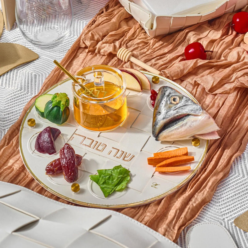 Rosh Hashanah 2025 painted tablescape featuring ceramic Seder plate with symbolic foods, olive wood platter, and gold oil bottle on linen napkin.