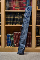 Scattered Fur Lulav and Esrog Case leaning against a wooden bookcase filled with Jewish sefarim.