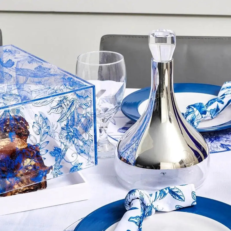 Shavuos French Toile 2024 tablescape featuring blue and white patterned dinnerware, glassware, and napkins on a white table setting.