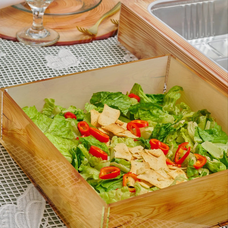 Wooden Shavuos tablescape with fresh salad greens, red peppers, and cheese in a natural wood serving tray for 2025 holiday dining.